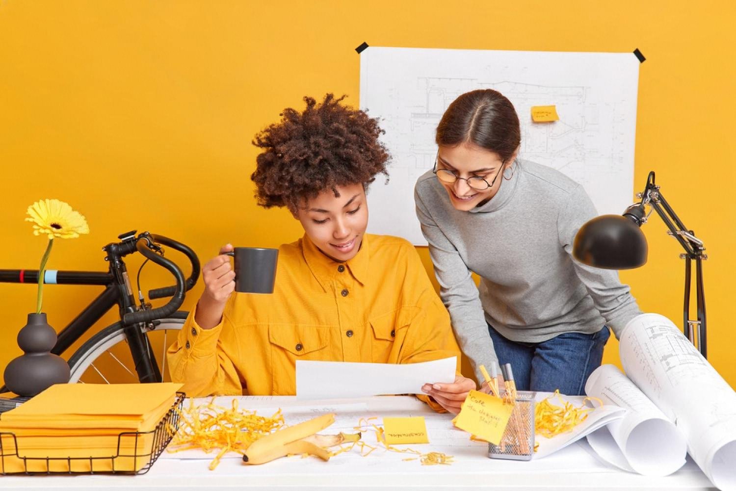 Two colleagues reviewing a document together in a bright, collaborative workspace